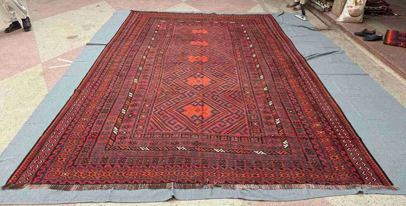 Handmade red and black Turkish Kilim rug styled on wooden floor – tribal geometric wool flatweave.