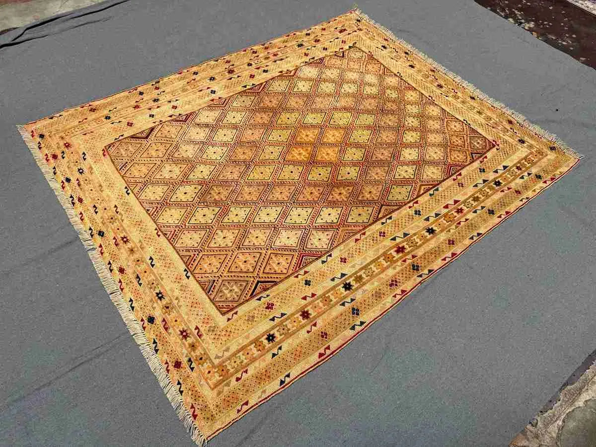 Floor display of beige, gold, and brown handwoven tribal rug in living room