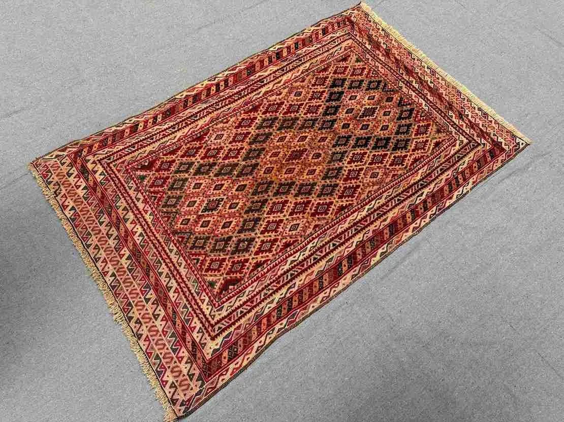 Top view of red tribal Afghan rug on wooden floor