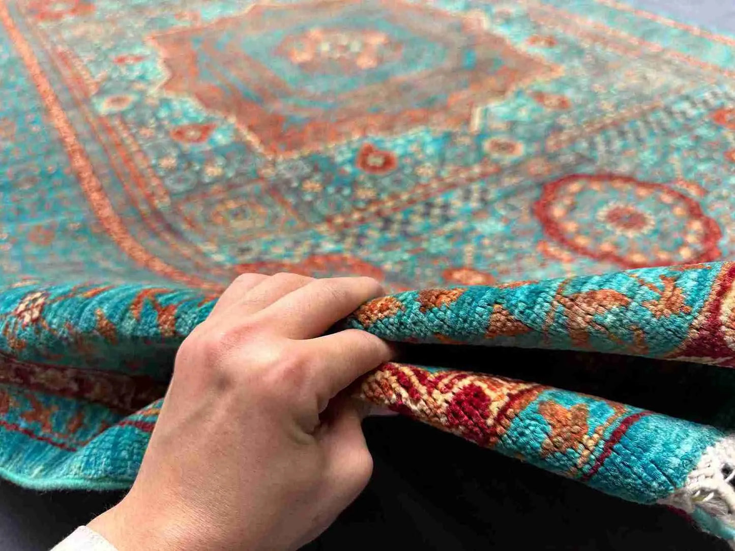 Hand-knotted vibrant Mamluk rug held in hand with rich wool silk texture