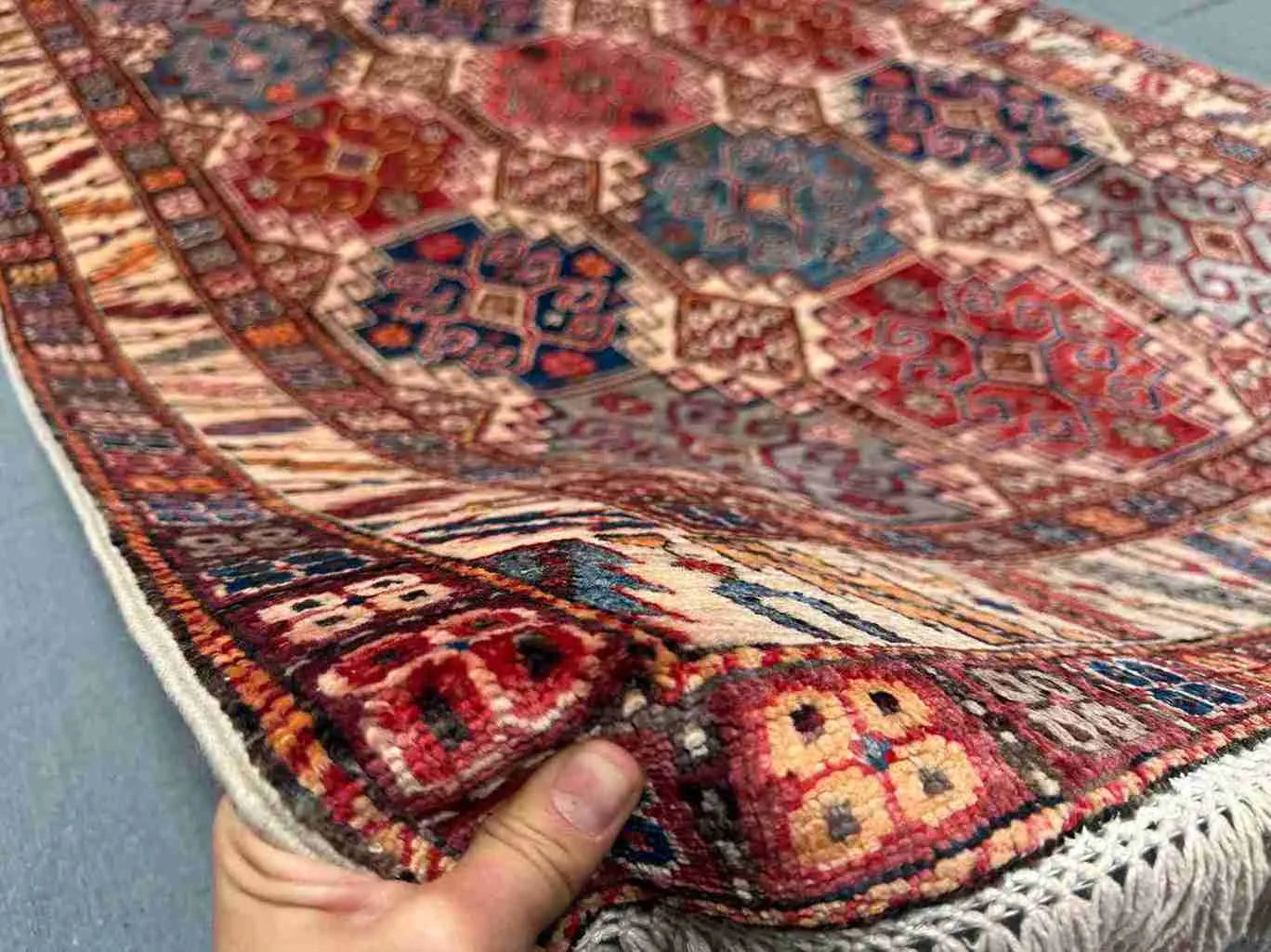 5x7 handmade Waziri rug in hand showing wool texture and tribal detail