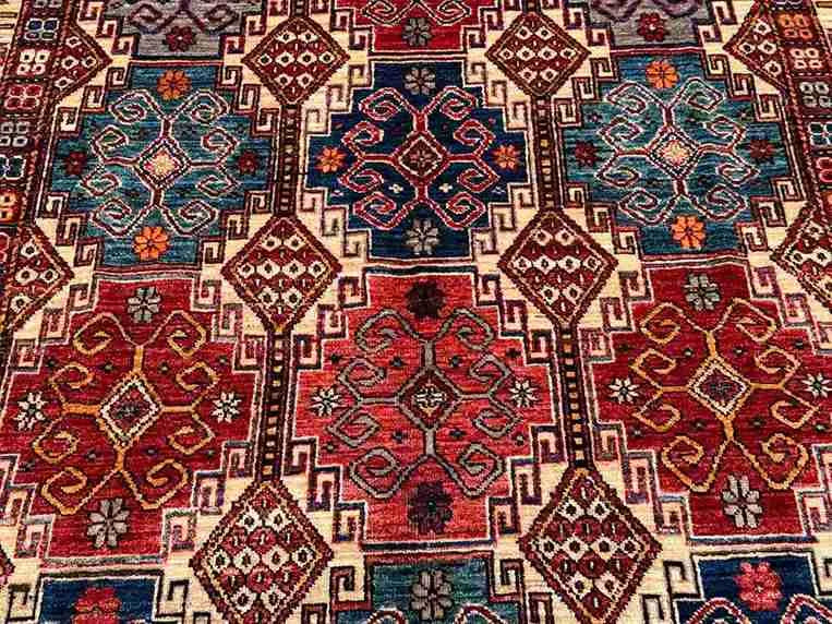 Close-up of tribal motifs on handmade 5x7 Waziri wool rug