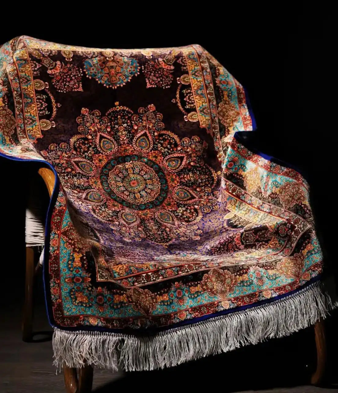 Luxurious Persian-style silk rug with rich jewel-toned colors and intricate floral medallion pattern draped over a wooden chair by Weirugs