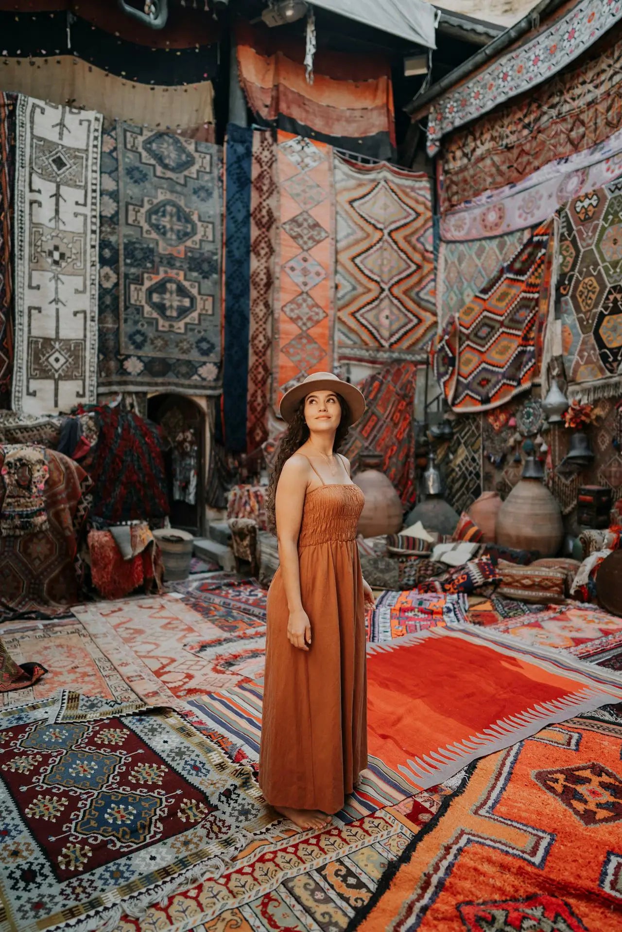 Woman in a vintage rug market surrounded by colorful handmade oriental and Persian rugs displayed on walls and floors