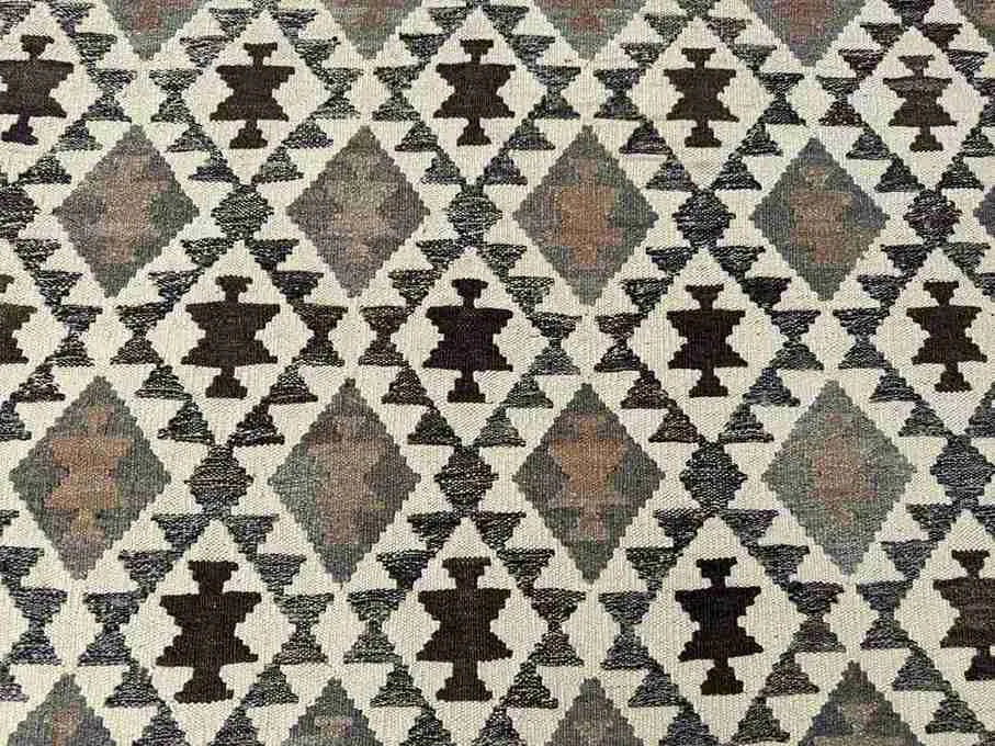 Close-up of wool flatweave Kilim rug texture – handmade and knotted in beige and brown tones.