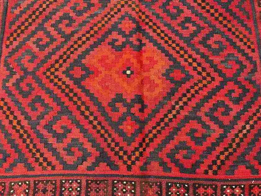 Close-up view of wool texture on Turkish Kilim rug – hand-knotted red and black flatweave.