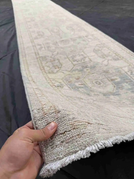 Handmade 15ft Oushak runner rug held to show authentic wool texture