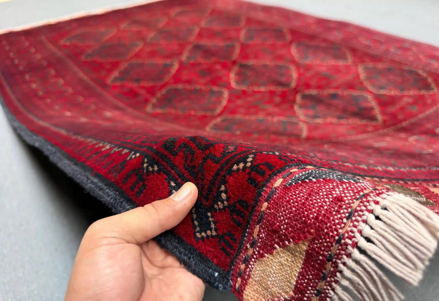 Handmade 5x8 red Afghan-style wool rug held in hands