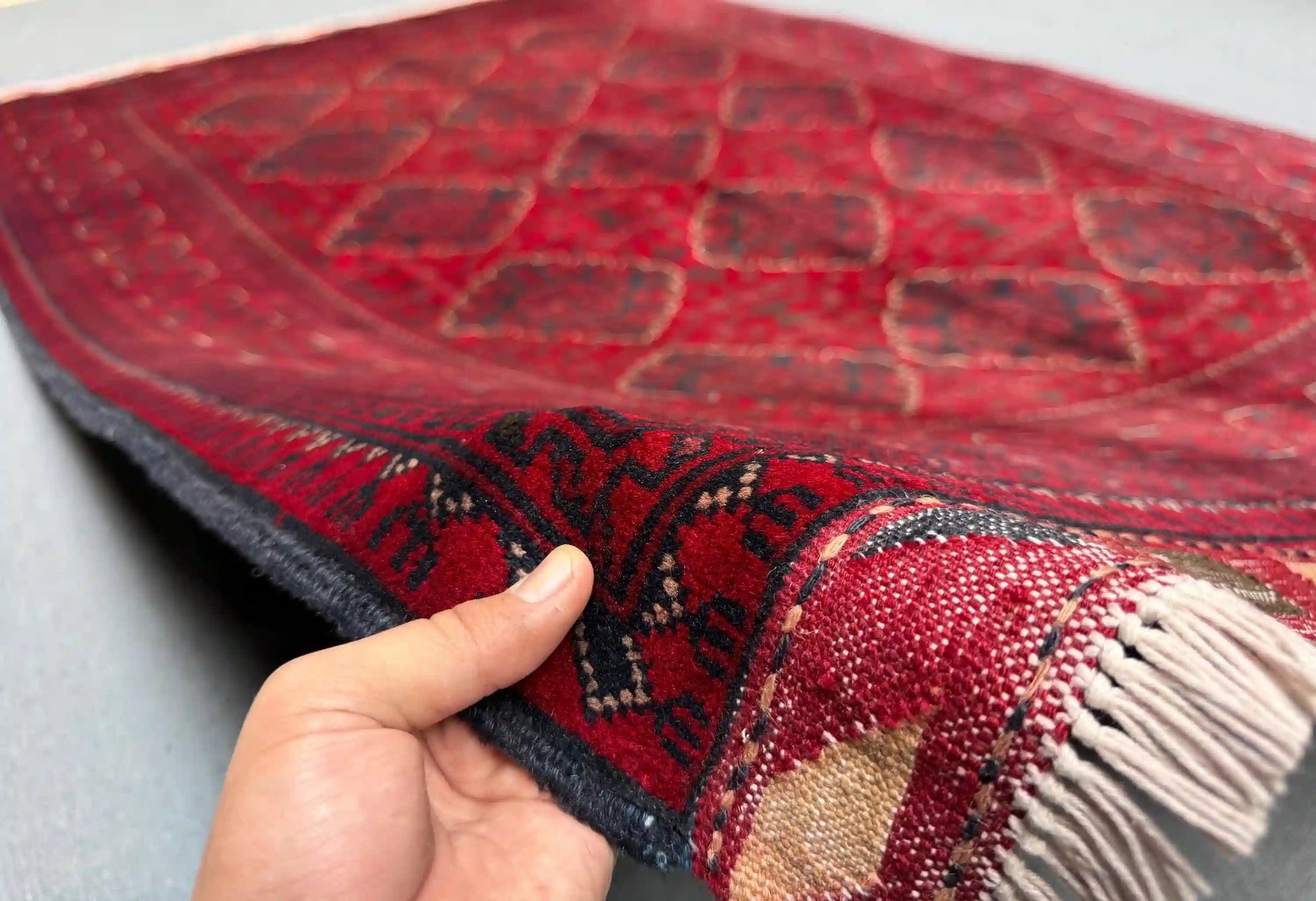 Handmade 5x8 red Afghan-style wool rug held in hands