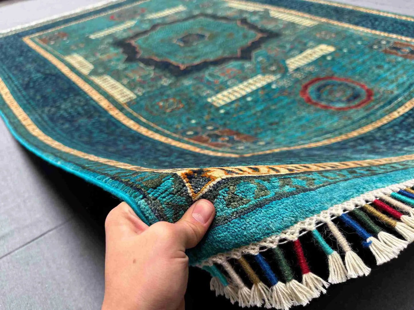 Handmade 6x7 Mamluk rug in teal green and gold held in hand
