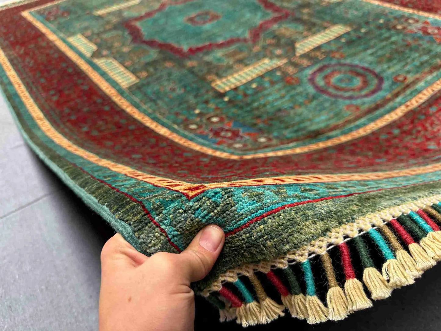 Handmade 6x8 red and teal Mamluk rug shown in-hand for detail