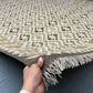 8x10 handmade Turkish Kilim rug held in hands – front view showing geometric wool flatweave in beige and brown.