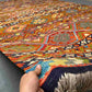Front view of 8x11 handmade Khorjin Kilim rug held in hands – vibrant multicolor geometric wool flatweave.