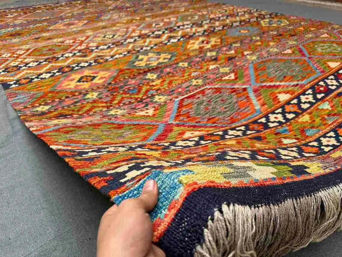 Front view of 8x11 handmade Khorjin Kilim rug held in hands – vibrant multicolor geometric wool flatweave.