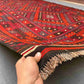 Large 8x12 Turkish Kilim rug in red and black held in hands – front view of handmade wool flatweave.