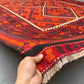 Handmade 8x12 Turkish Kilim rug held in hands – front view of red and black geometric wool flatweave.