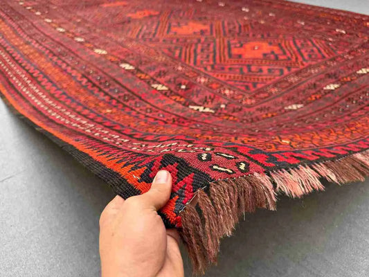 Front view of 8x13 handmade Turkish Kilim rug in red and black held in hands – tribal wool flatweave.
