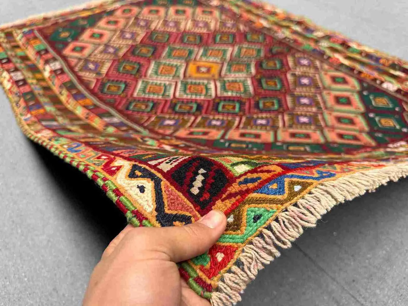 Handmade Persian Afghan kilim rug in hand showing tribal wool weave