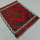 Small Afghan Kilim rug styled on wooden floor – vibrant red wool flatweave for home decor