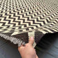 Handmade Kilim rug in black and ivory held in hand, flatweave detail