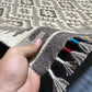 Person holding authentic handmade Turkish Kilim rug in black and white, 5x7 ft wool flatweave.