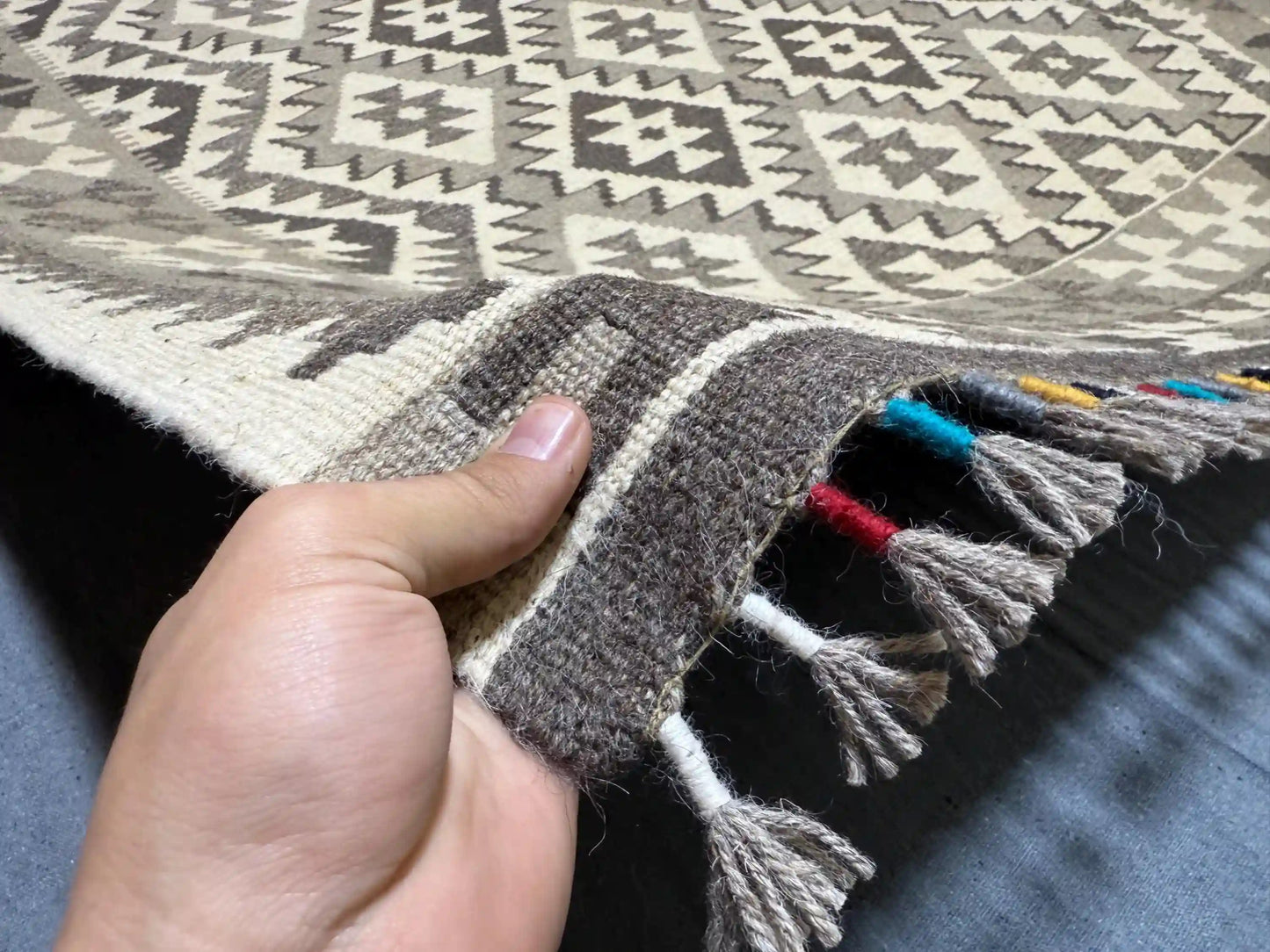 Person holding authentic handmade Turkish Kilim rug in black and white, 5x7 ft wool flatweave.