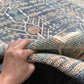 Handmade 5x9 blue and beige wool rug held to show thickness and weave