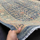 Handmade 5x9 blue and beige wool rug held to show thickness and weave