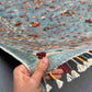 Hand showing the texture of 6x8 blue & gray oriental wool rug