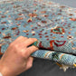Detailed hand-held view of handmade floral wool carpet