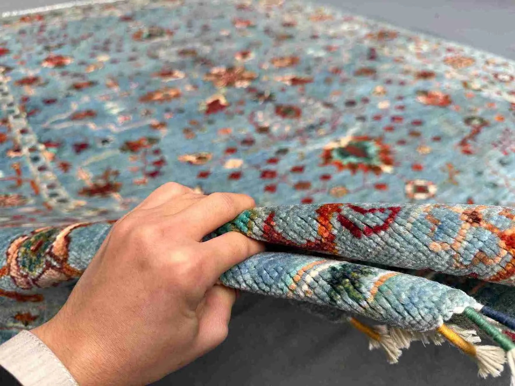 Detailed hand-held view of handmade floral wool carpet