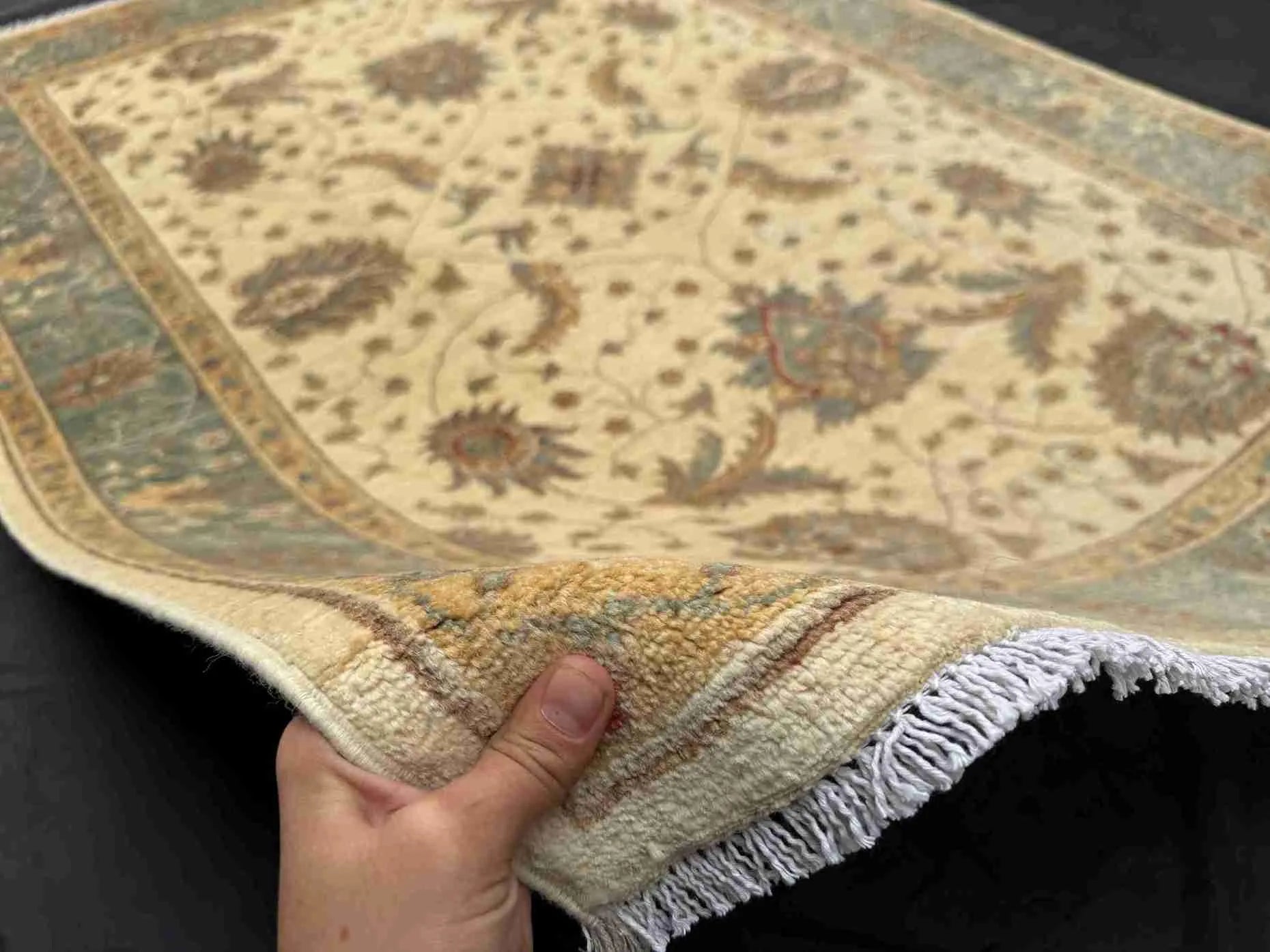 Authentic 6x8 handmade Chobi rug shown in hands, beige and green wool