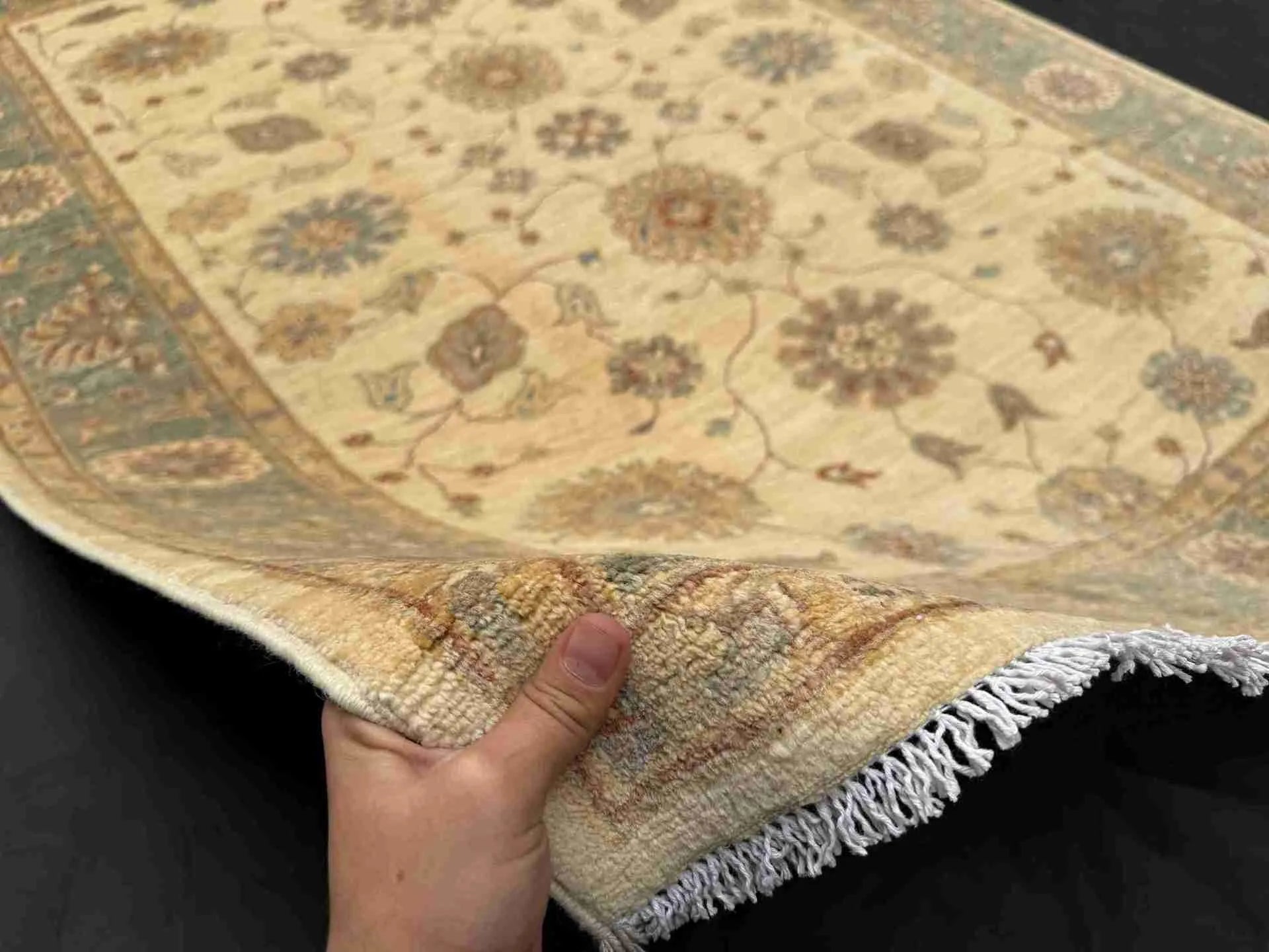 Authentic 6x8 Chobi rug in hands showing hand-knotted wool texture