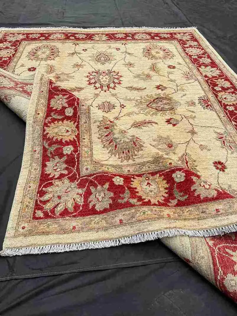 Folded view of handmade red and cream Chobi wool rug