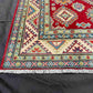 Corner detail showing woven Turkish-Kazakh motifs on red-beige rug