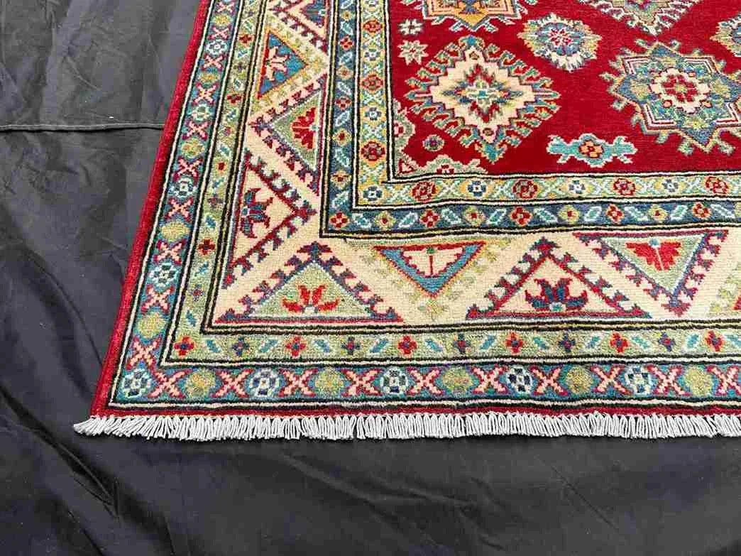 Corner detail showing woven Turkish-Kazakh motifs on red-beige rug