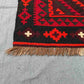 Corner detail of Turkish Kilim rug – handwoven red and black wool flatweave with tribal design.