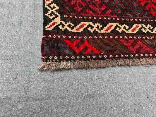Corner detail of vintage Afghan Kilim rug – small red wool flatweave with knotted tribal accents.