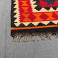 Corner detail of red and orange Turkish Kilim rug – handmade wool flatweave with tribal pattern.