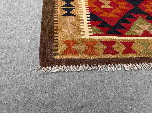 Corner detail of vintage Turkish Kilim rug – knotted multicolor wool flatweave with tribal patterns.