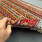 Handmade vintage Turkish kilim rug held in hands showing floral and stripe design