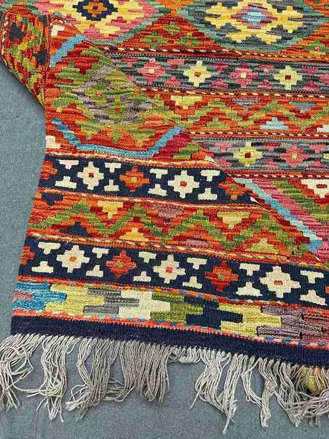 Folded 8x11 Khorjin Kilim rug – vibrant multicolor wool flatweave with tribal design.