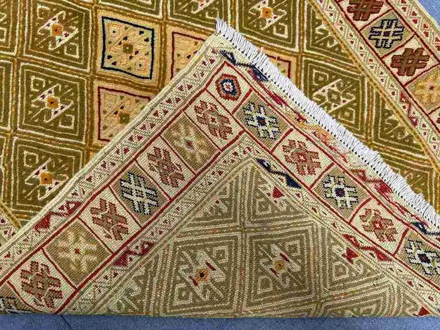 Folded Persian kilim rug showing olive and gold tribal craftsmanship