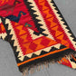 Folded handmade Turkish Kilim rug – red and orange wool flatweave with tribal details.
