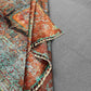 Folded view of blue, orange, and red Mamluk wool rug