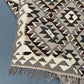 Folded view of small earthy-tone Kilim rug – handmade wool flatweave.