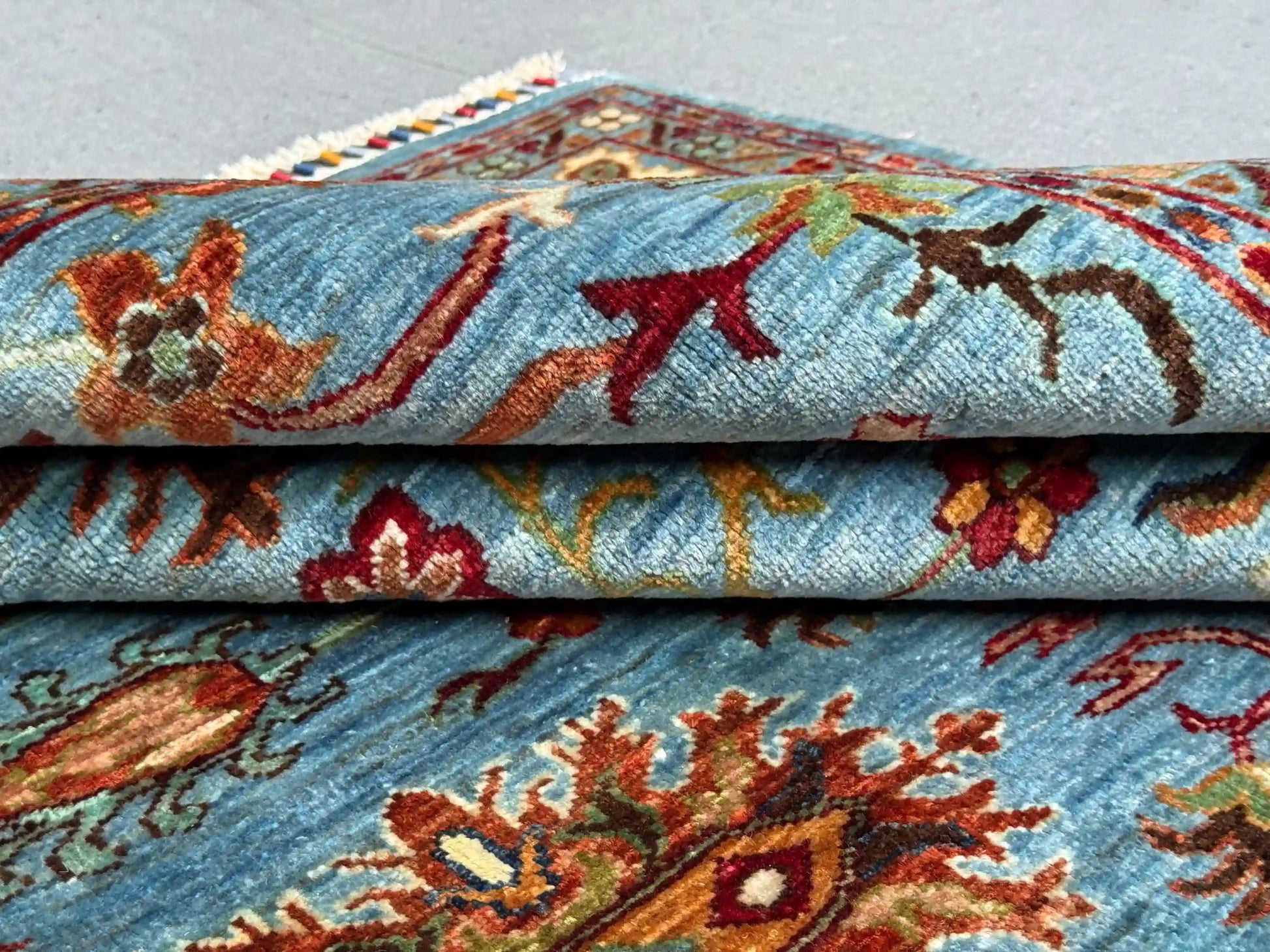  Close-up of folded red and blue Sultani Persian wool rug