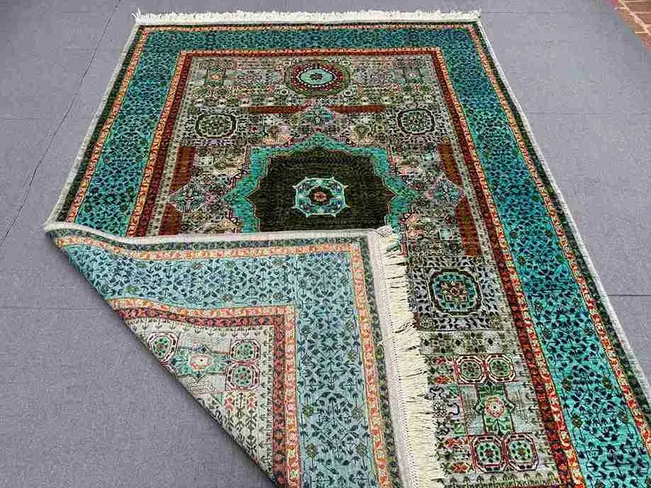 Folded view of handmade turquoise wool Mamluk rug – showing silk detail