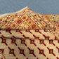 Folded view of beige and red tribal rug showing wool texture