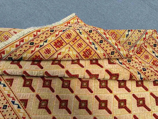 Folded view of beige and red tribal rug showing wool texture